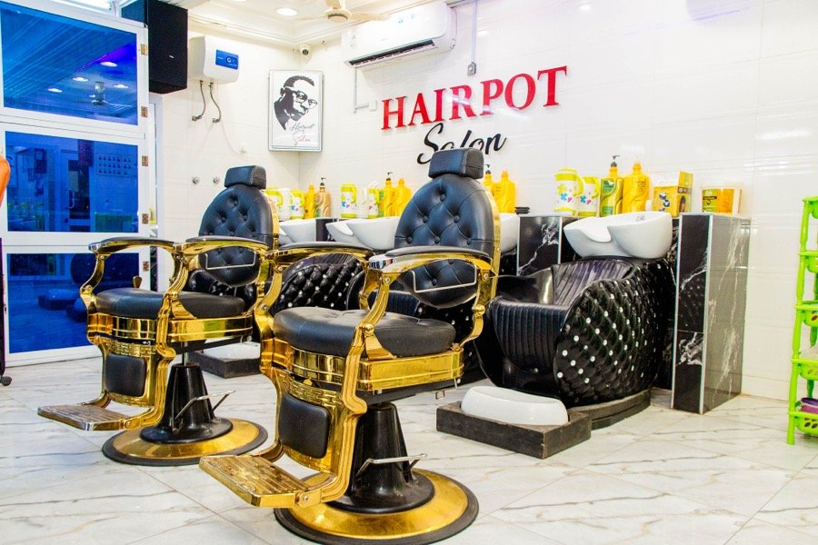 Gold-trimmed barber chairs beneath a framed portrait, wash basins alongside