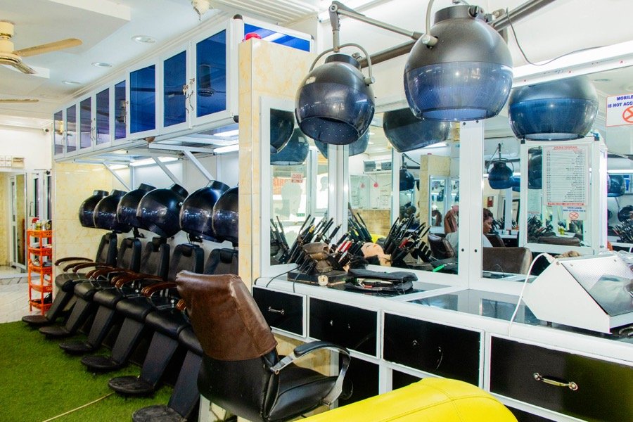 Row of hooded hair dryers over styling chairs on a green turf floor