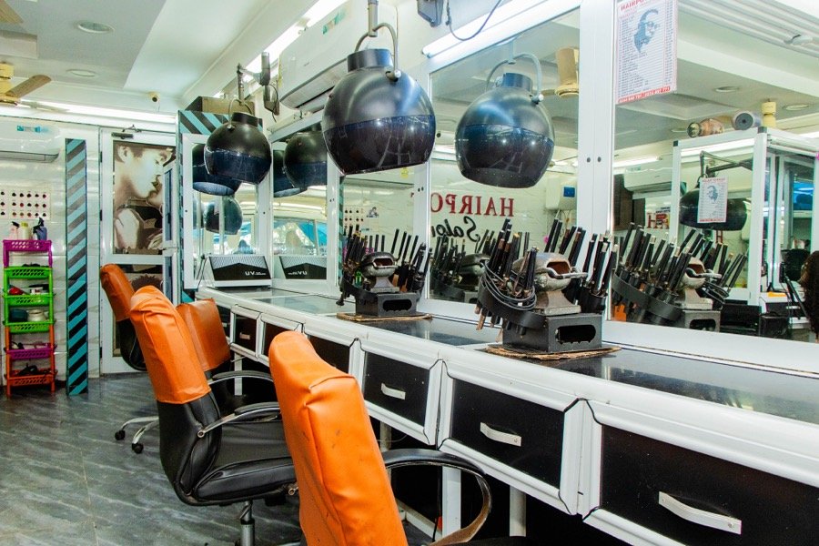 Row of hooded hair dryers with orange styling chairs