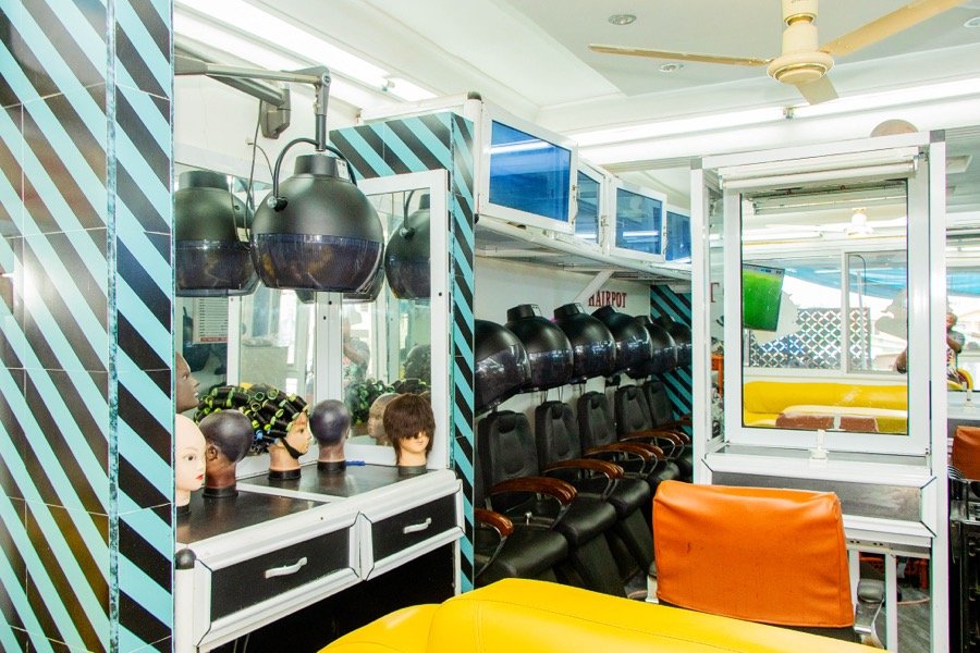 Styling prep area with mannequin head forms and a turf-floor room beyond