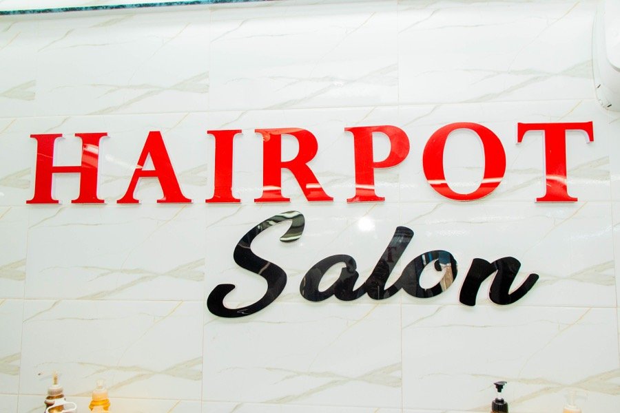 Hairpot Salon wordmark sign mounted on a tiled wall