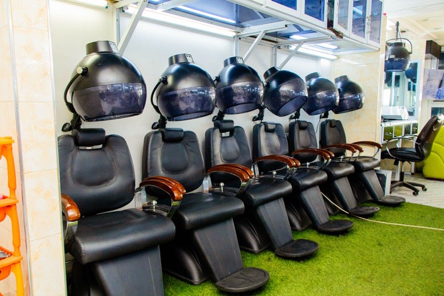 Wash basins and hooded dryers on a green turf floor