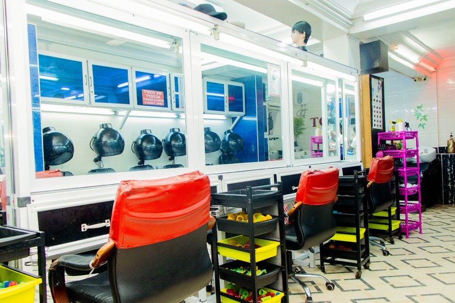 Row of styling stations with hooded hair dryers and red chairs