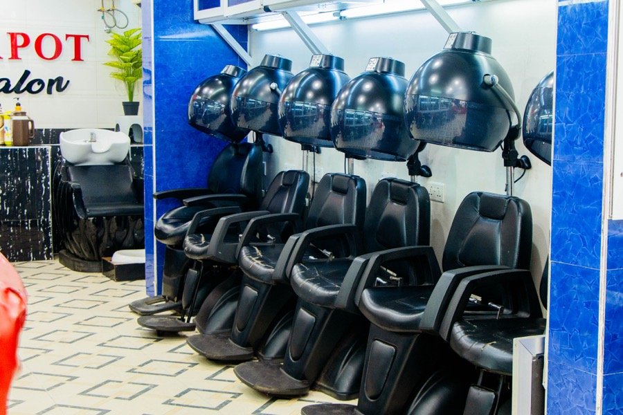 Row of hooded hair dryers along a blue-accented wall